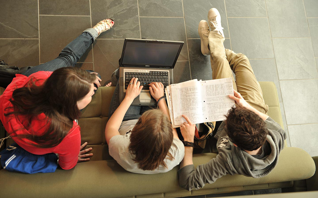 Three students working on a laptop computer