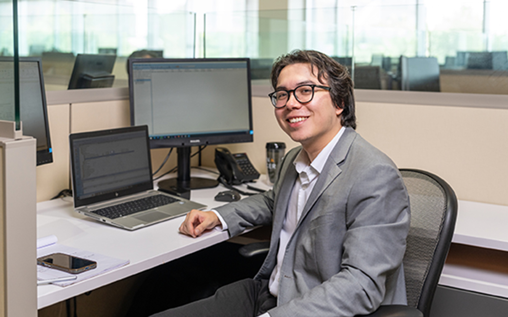 student poses at computer at internship student poses at computer at internship