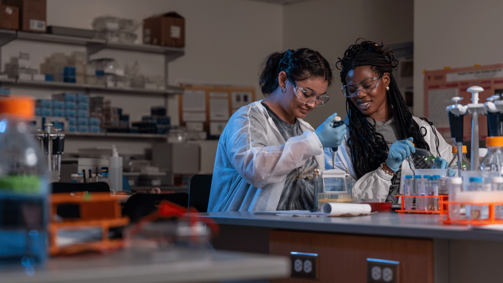 Two female students wearing lab gear working in the science lab