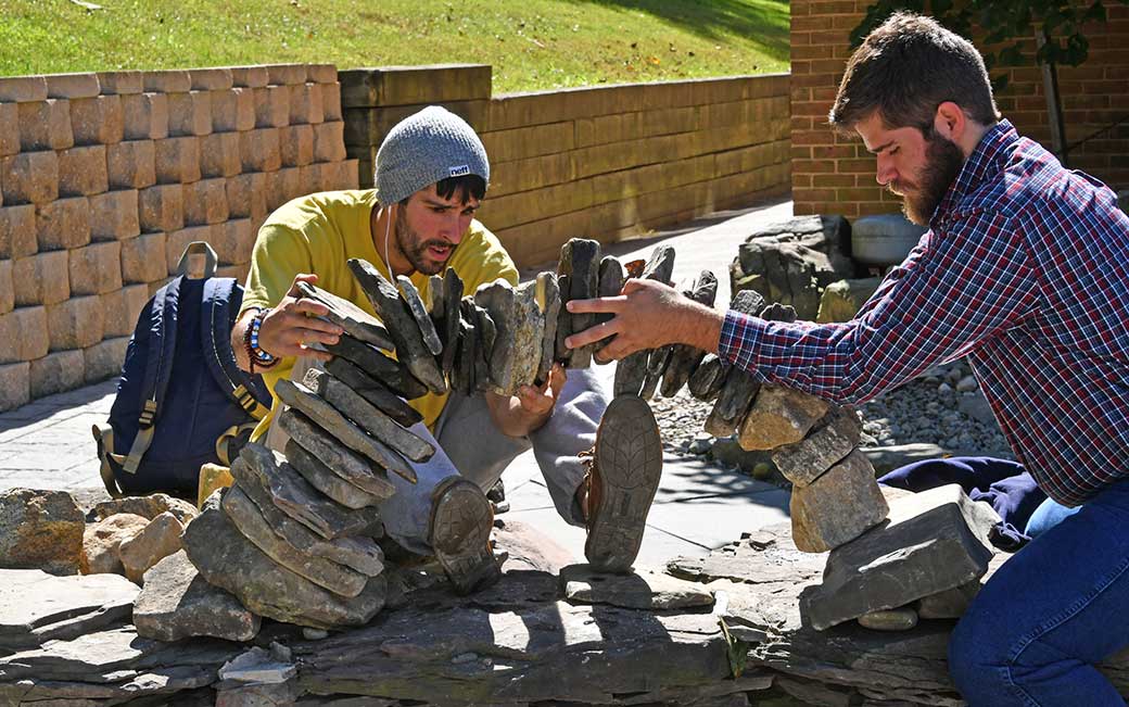 Senior Tyler Bohn, left, builds rock towers around campus as a way to focus and relieve stress.