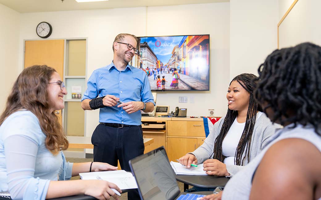 TU graduate students converse cheerfully in a TU classroom