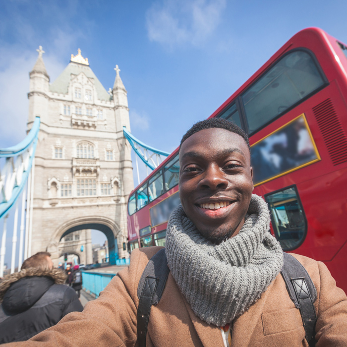 Man smiling in front of a red double decker bus in London