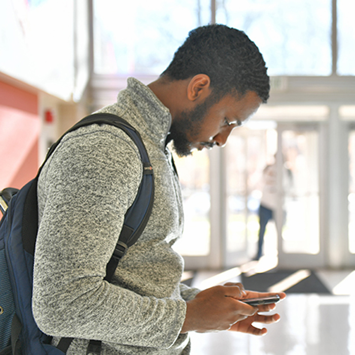 male student reading smartphone screen