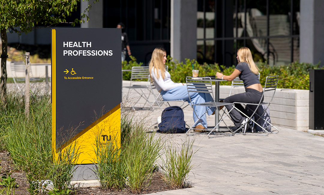 Students walking on TU campus near wayfinding signage