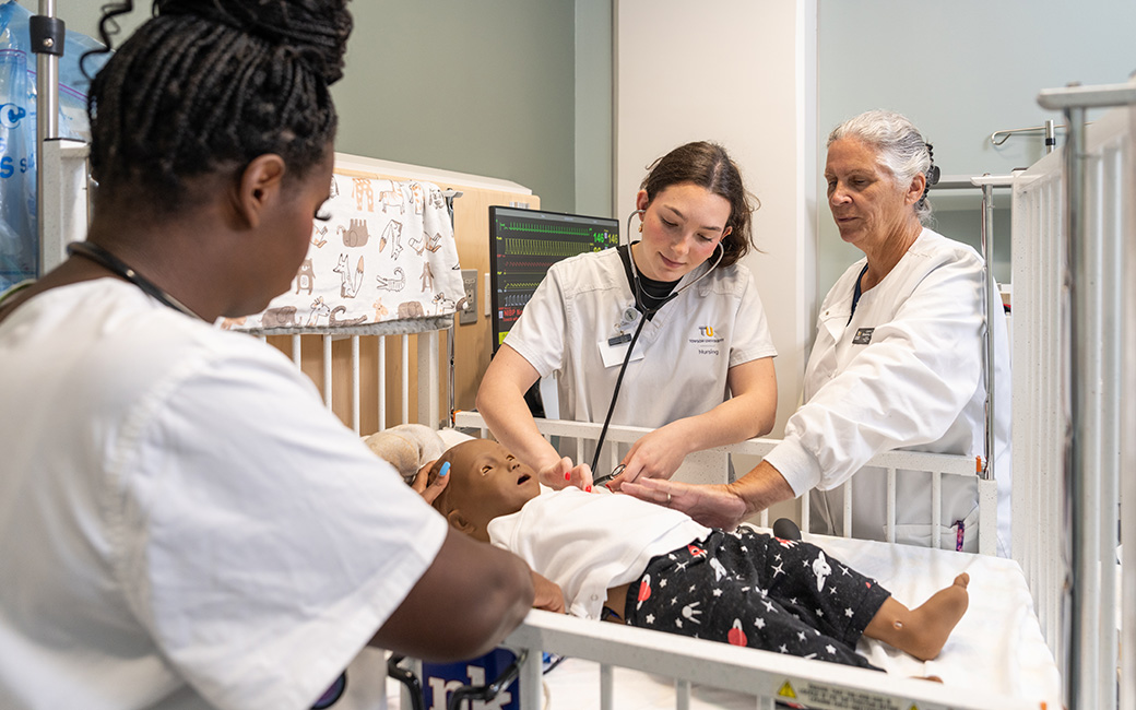 TU nursing students pretending to take a baby's heart rate