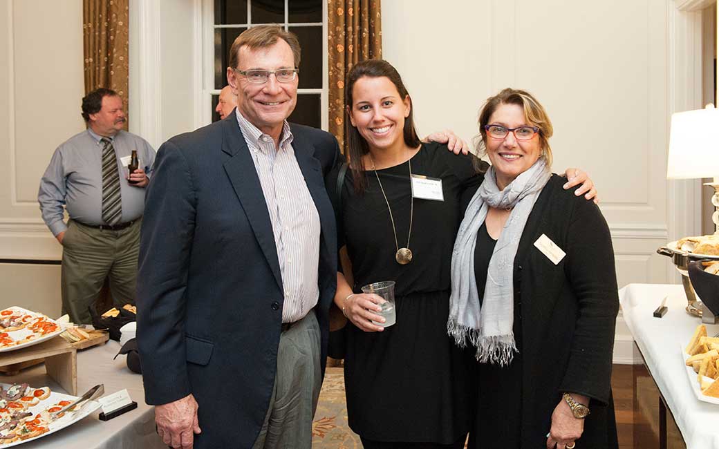 two alums with the dean at a networking event