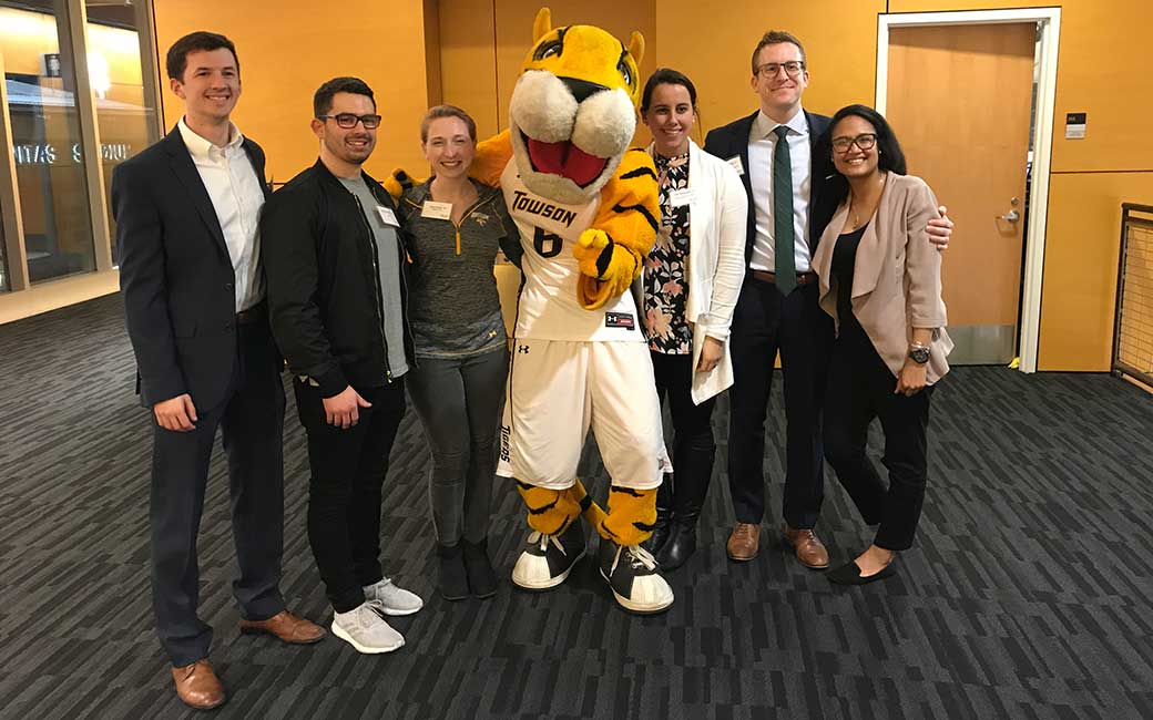 Young alumni posing with Doc the Tiger at one of the TU men's basketball games