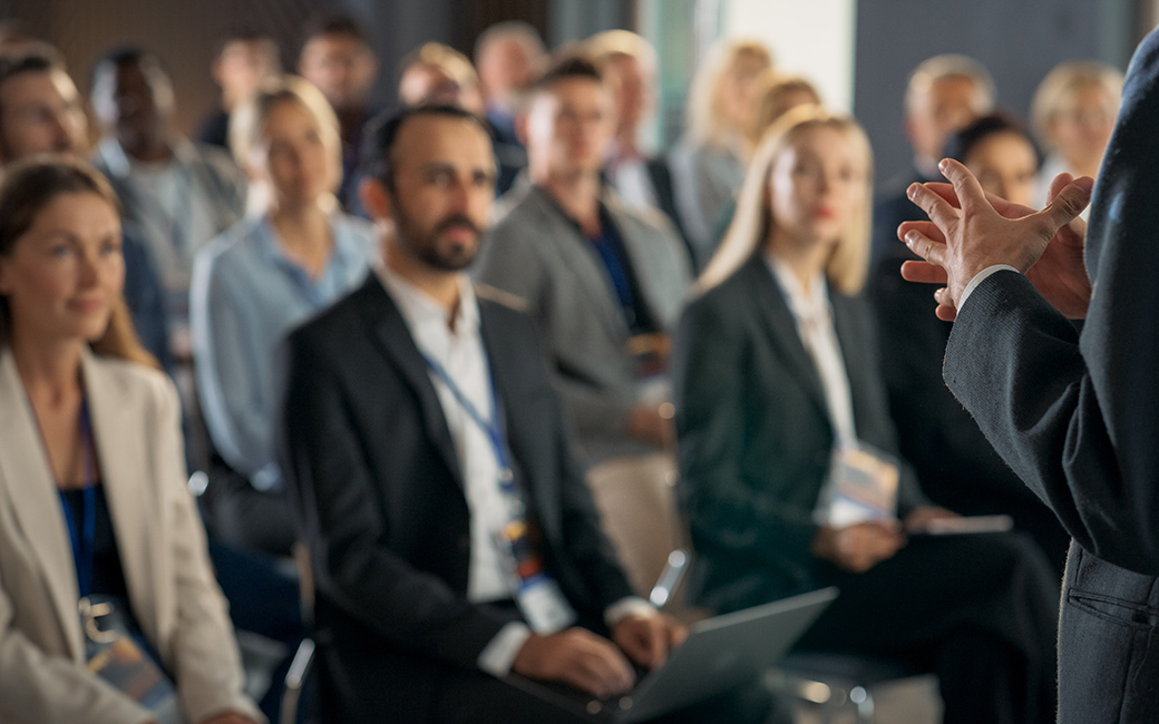 An audience at a symposium listen to a speaker