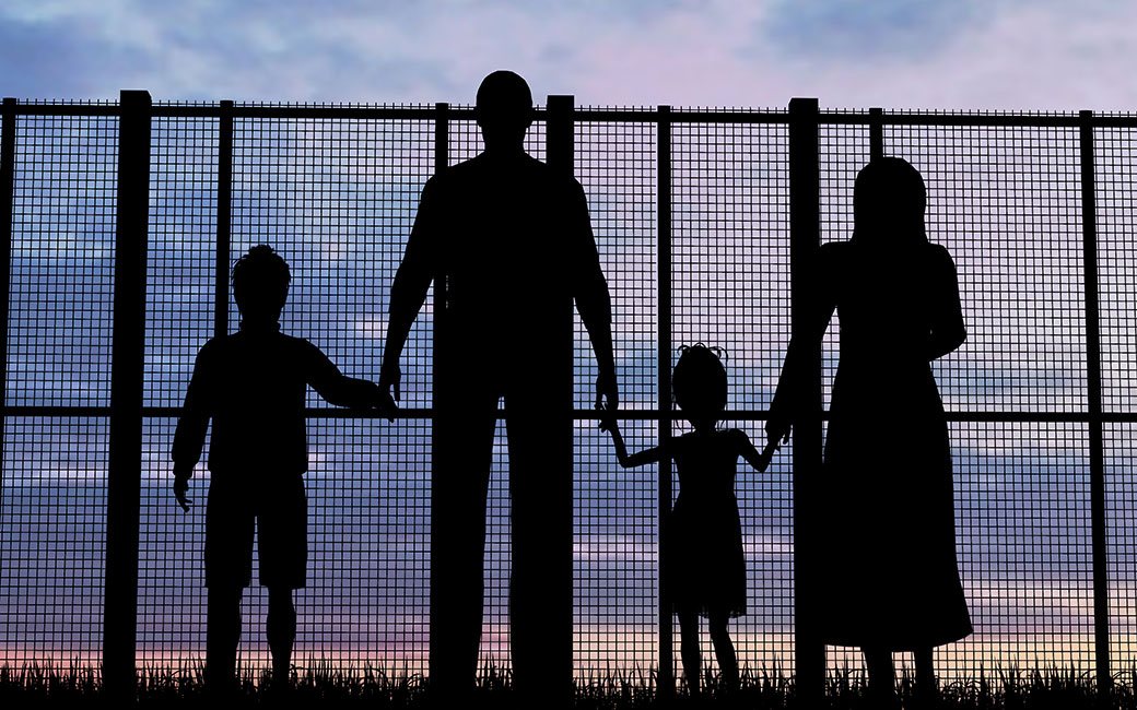 family in silouette in front of a fence