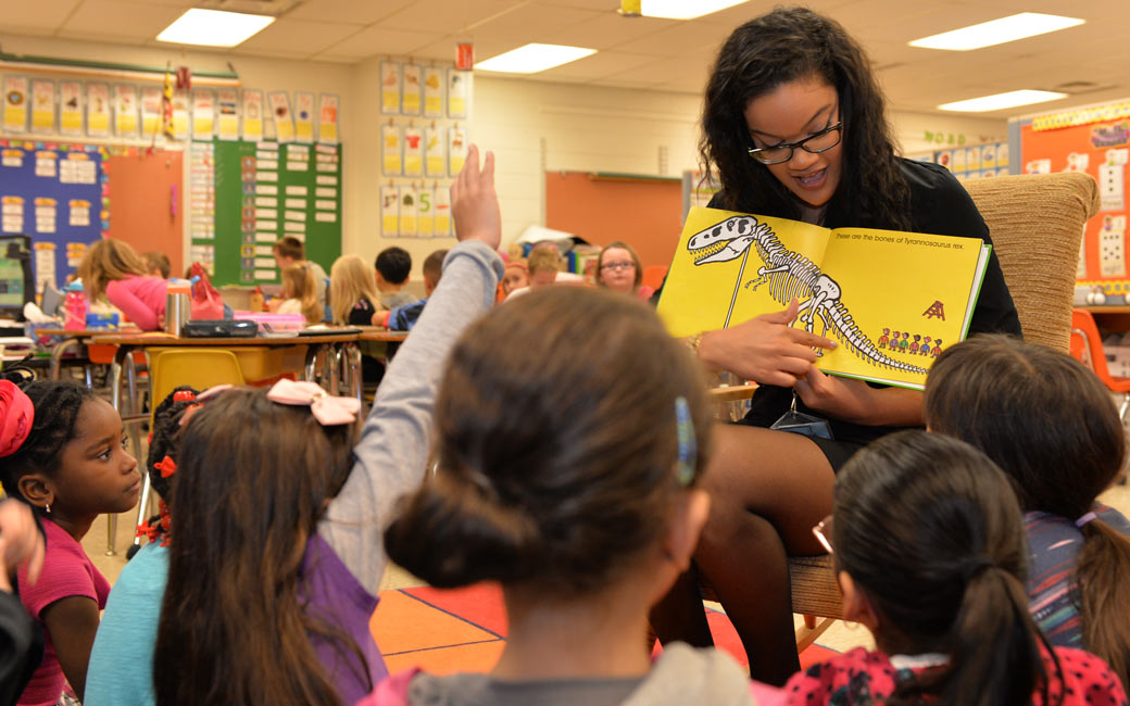 Student teacher reading book to kids in classroom