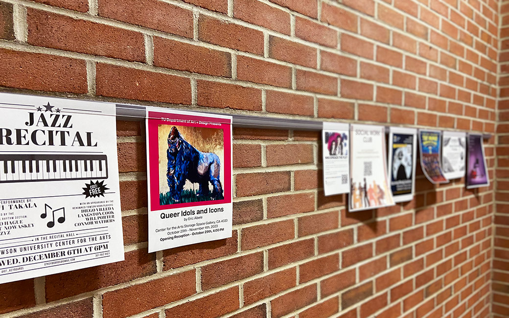 A row of hung up fliers line a brick wall