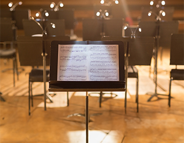 Fresh new sheet music sits on a music stand and lit stage