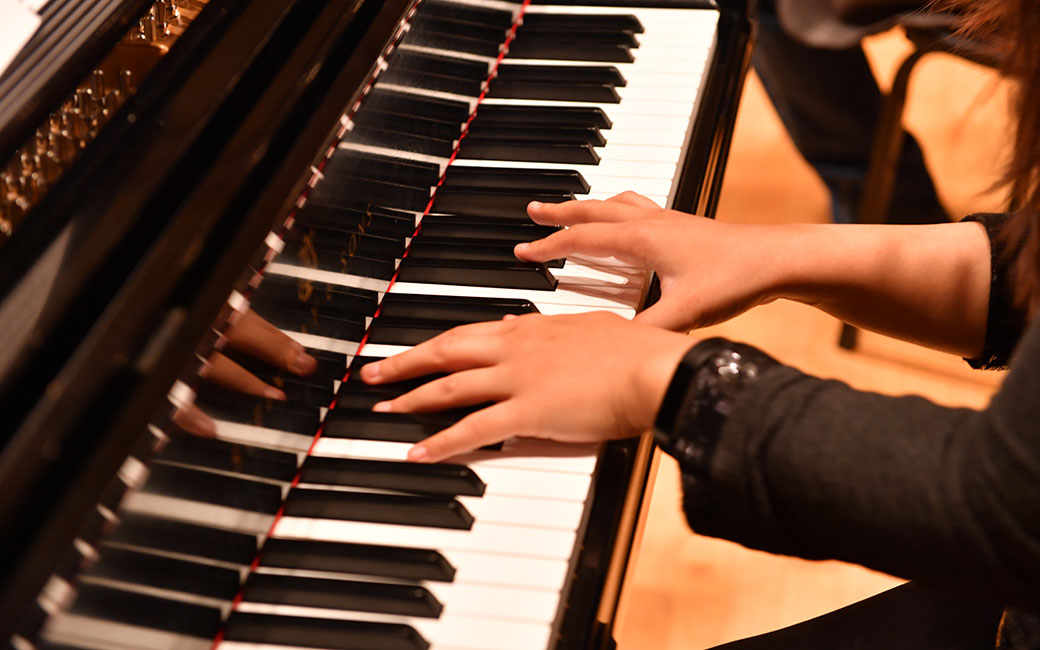 A close up on hands as they play a piano