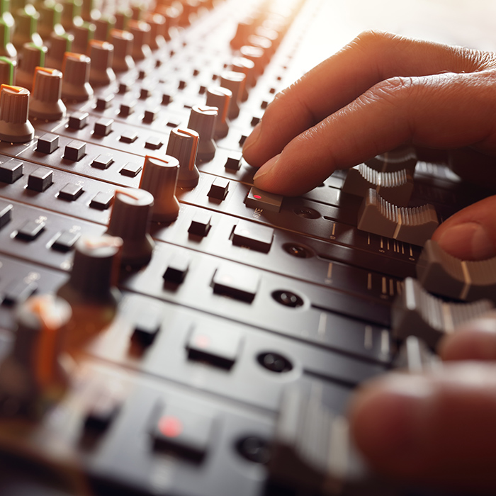 A close up of a studio engineer's hand operating a mixing board