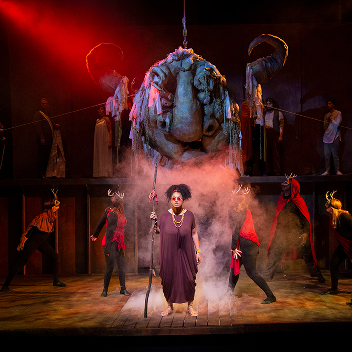 Actress stands in middle of stage with group surrounding her