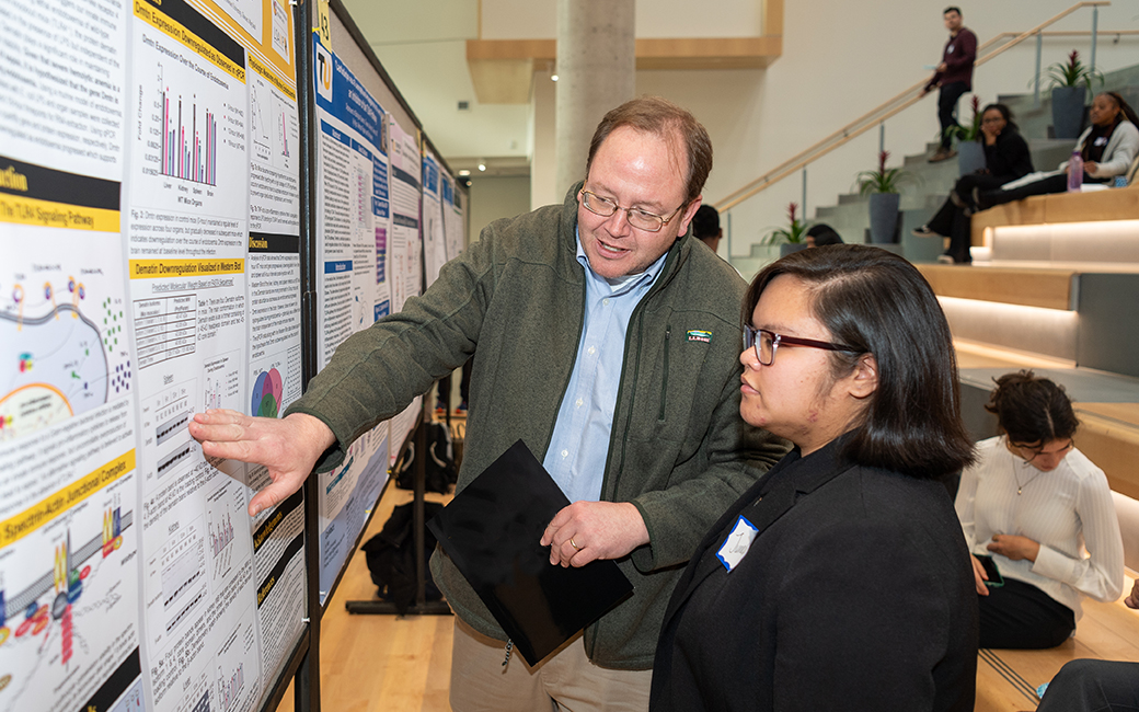 Professor discusses poster with student