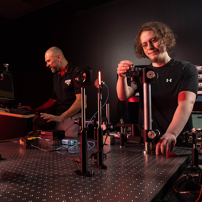 student and professor at optics table