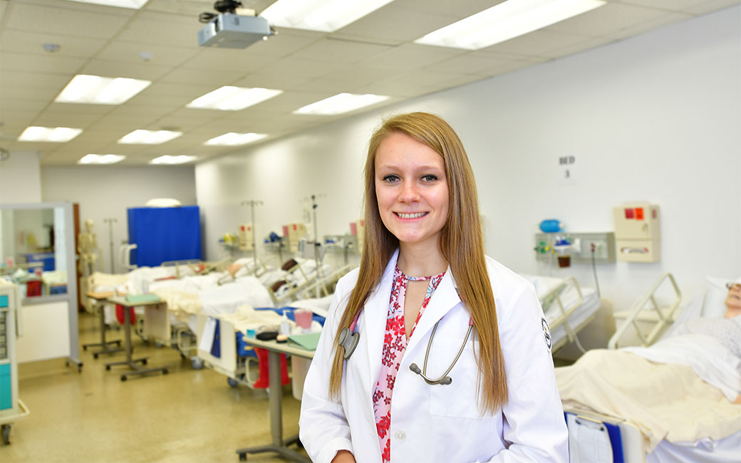 Honors student Abbie Poindexter standing in front of nursing simulation room