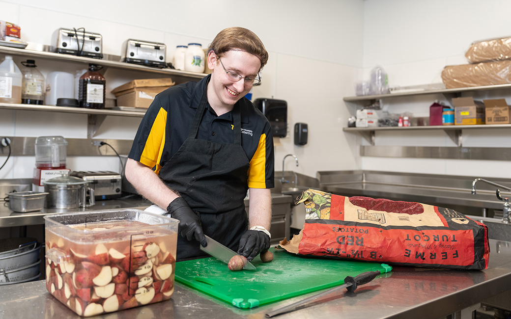 Andrew Martini cutting potatoes in an industrial kitchen