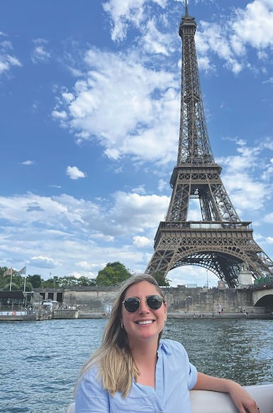 Allison Brown smiles in front of the Eiffel Tower