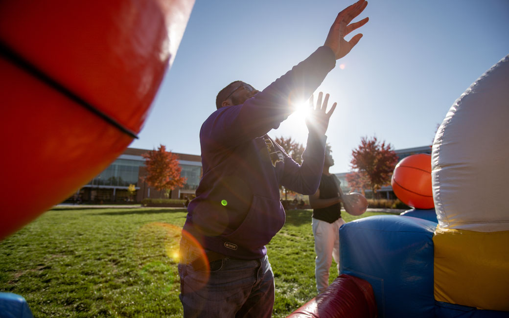 A student shoots a basketball at an inflatable during the block party