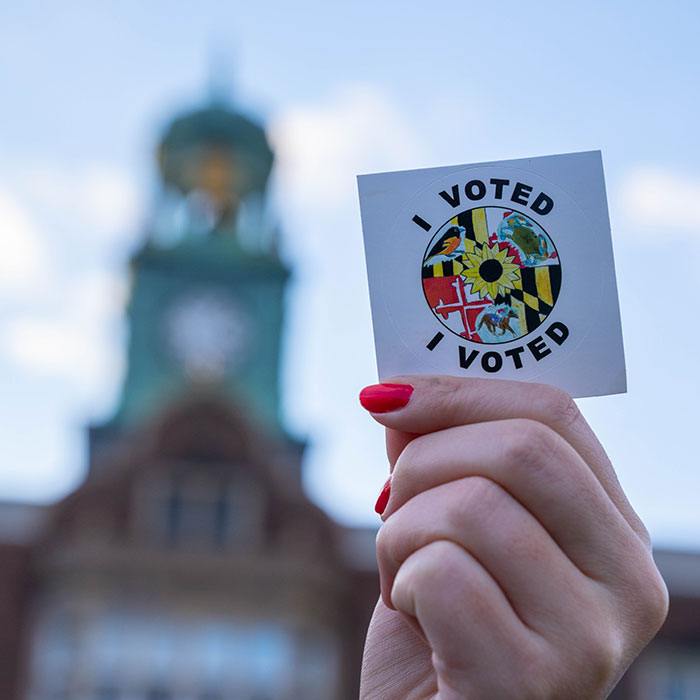 Hand holding an "I voted" sticker