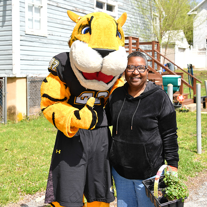 TU mascot doc and a Towsonian posing together in front of a historic home