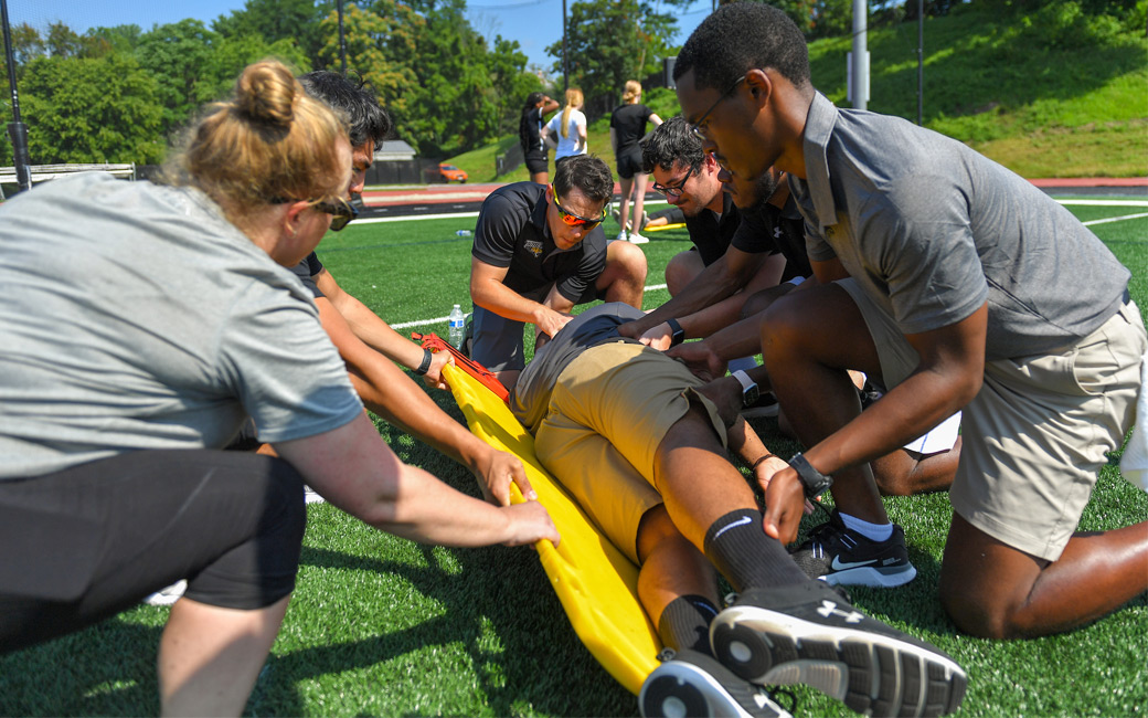 Students practicing moving a patient to a spine board