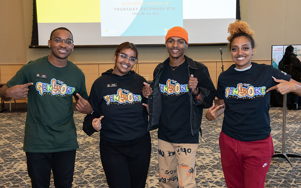 Four students pointing to their t-shirts