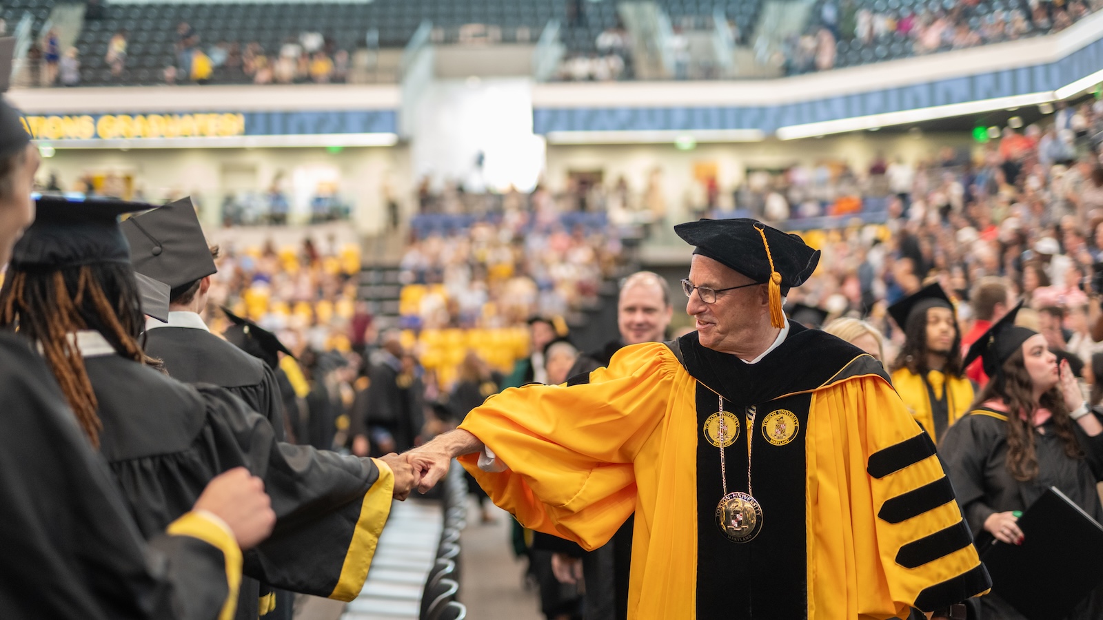 TU President Ginsberg gives students a fist bump during Commencement ceremonies