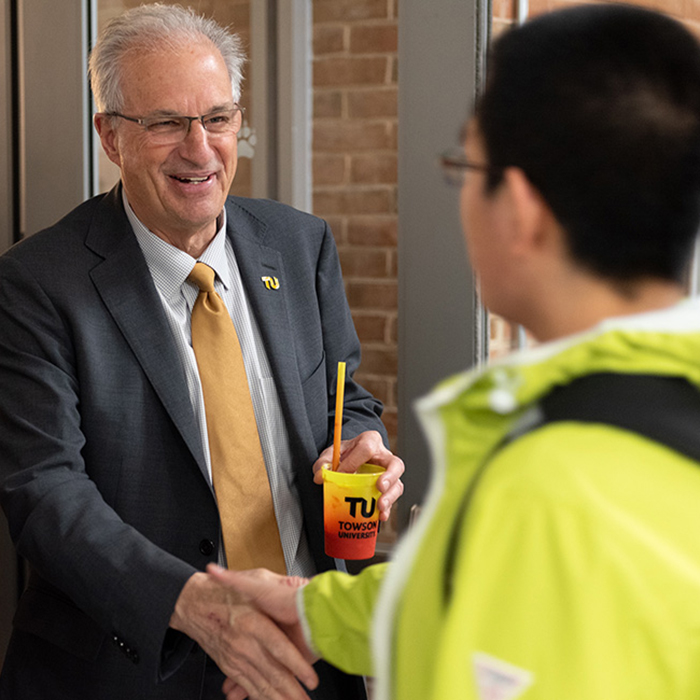 President Ginsberg shaking hands with a student