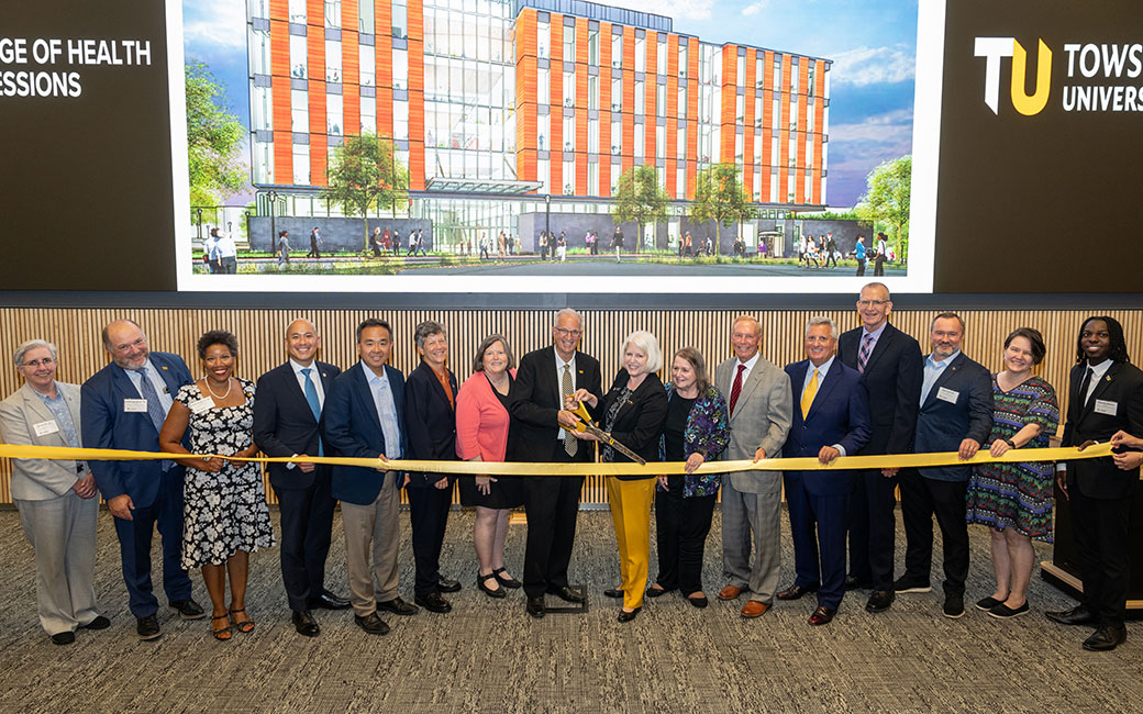 Several people in line while Dr. Ginsberg cuts the ribbon with giant scissors