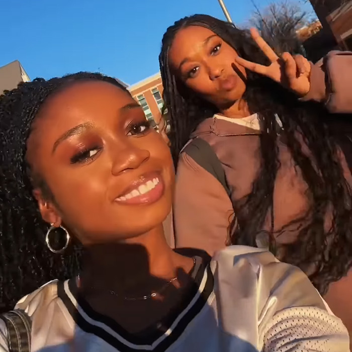 Two women posing for a selfie; one smiling and one holding up a peace sign