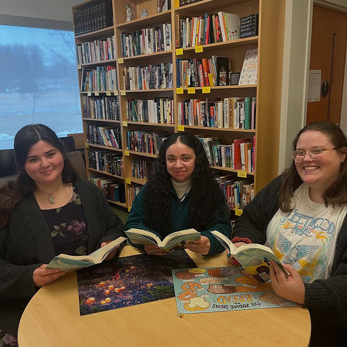 Three women sitting around a table and holding books