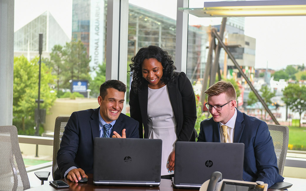 3 people looking at a laptop