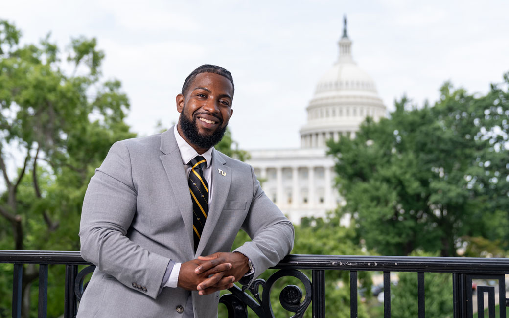 Alum Jamal Washington leans on a railing overlooking the Capitol in Washington DC