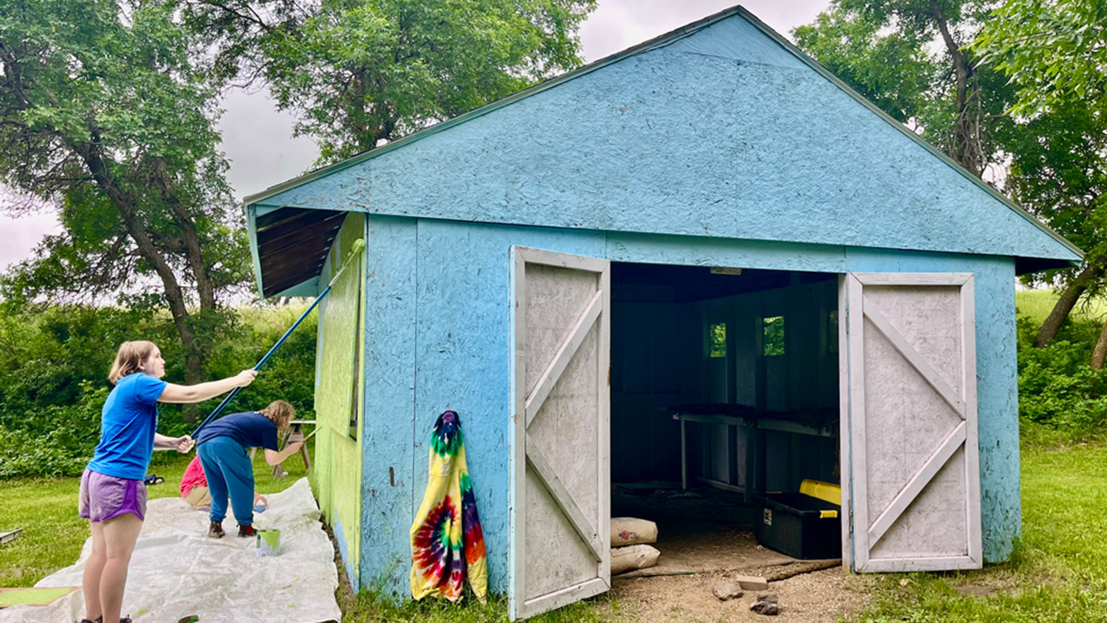 Two women painting a shed