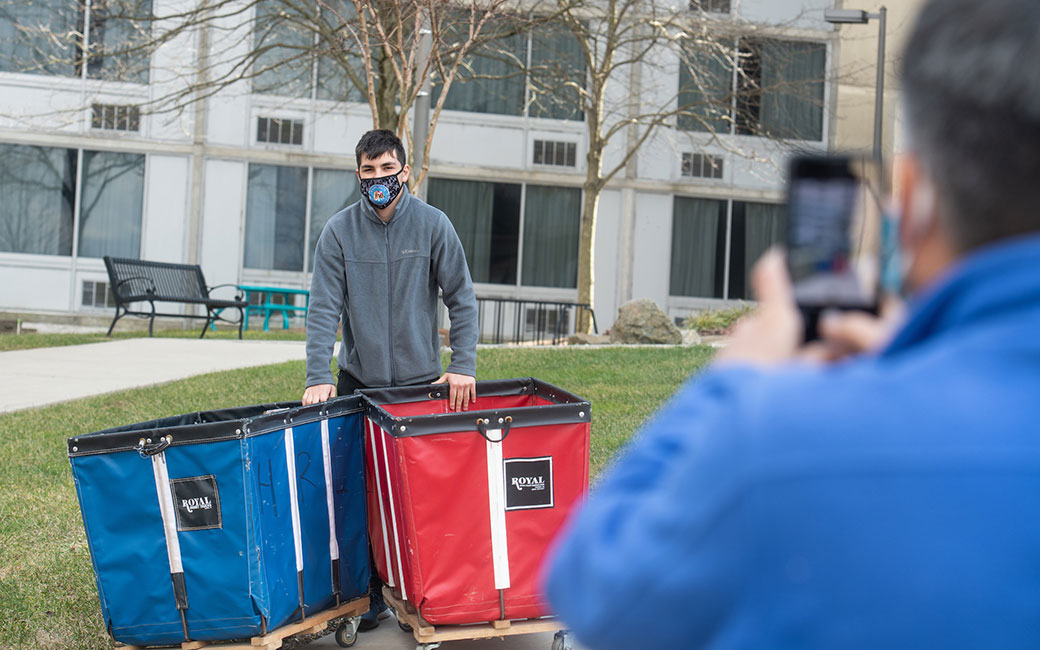 Man takes cell phone photo of student with carts