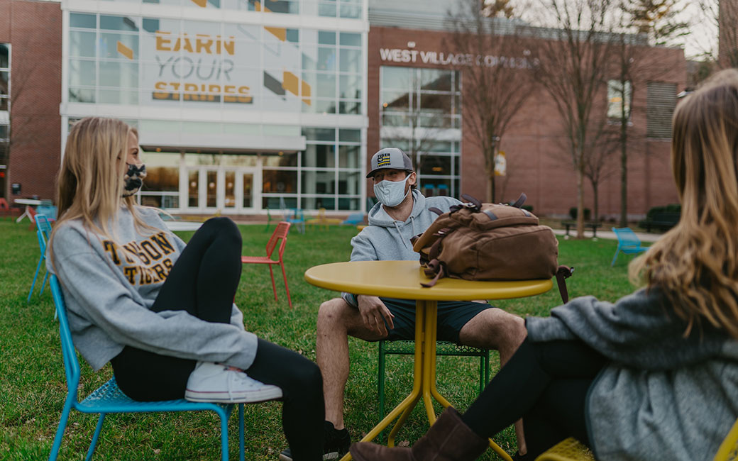 Masked students seated at outdoor tables