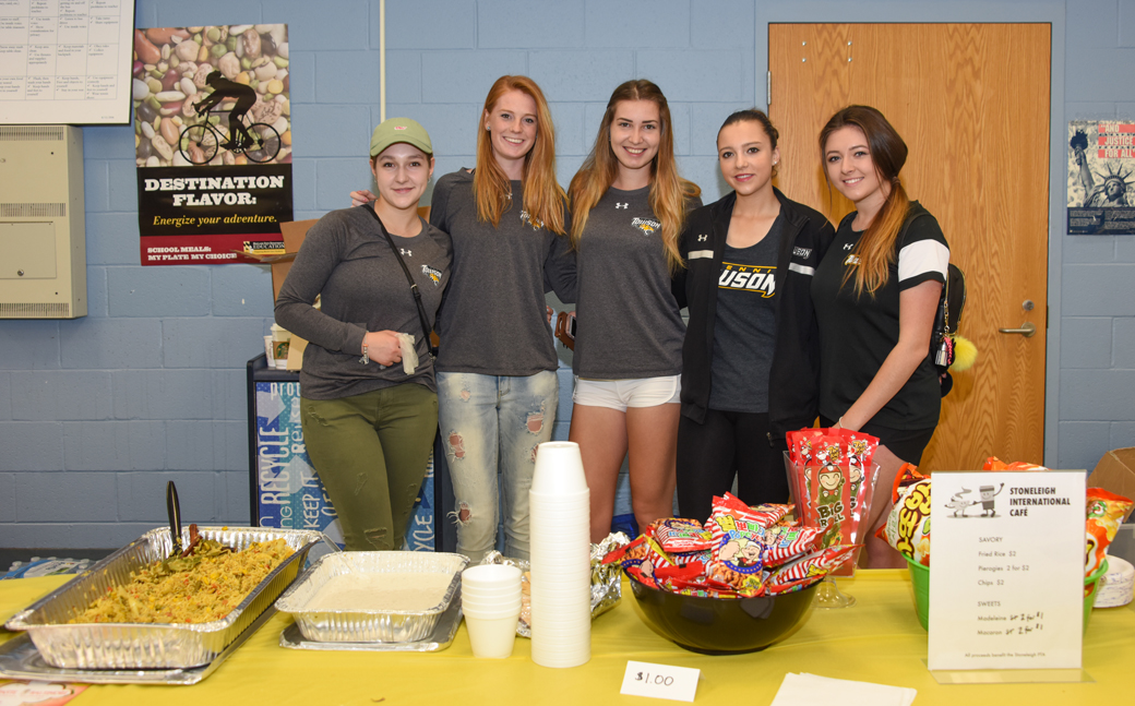 Towson University tennis team members (from left to right) Yevgeniuya Shusterman (Ukraine); Renate Van Oorschodt (Netherlands); Barbora Vasilkova (Slovakia) Sophie Lesage (France) and Nicole Shakhnazarova (England) pose behind concession stand at the Stoneleigh Elementary International Festival. The international student-athletes came to talk to students during the festival on Saturday, February 25. 