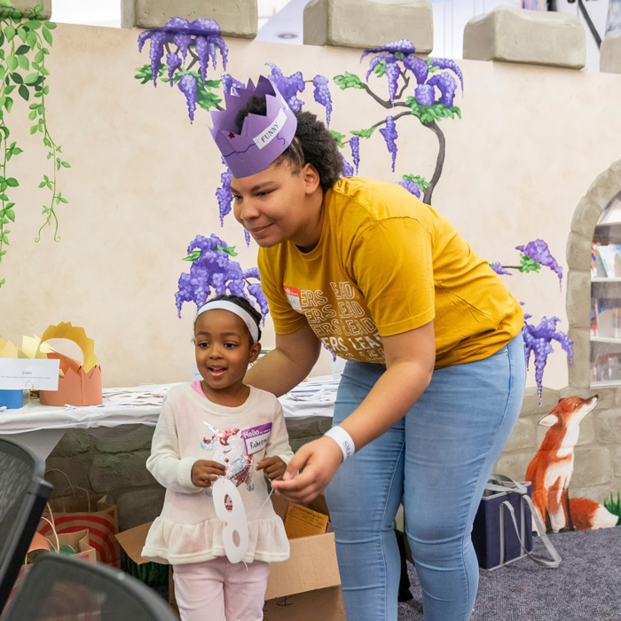 A TU student in the Tigers Lead program does a arts and crafts project with a child during a workshop at the Towson branch of the Baltimore County Public Library