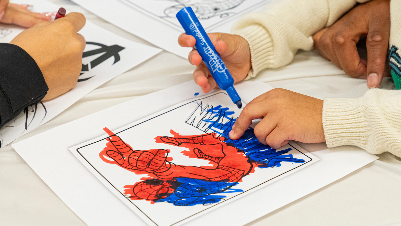 A kid colors a picture spider man during an arts and crafts projects during the Tigers Lead workshop at the Towson Branch of the Baltimore County Public Library