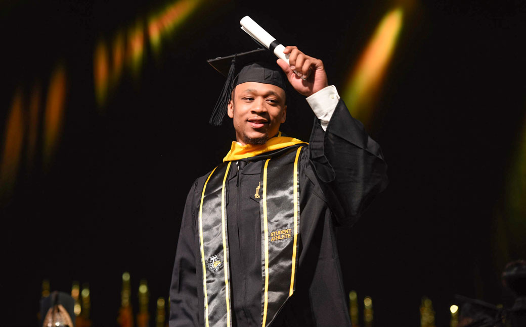 Former TU men's basketball player John Davis waves to the crowd after walking across the Commencement stage during 2017 Spring Commencement. Davis received a bachelor's degree in communications studies, while teammate Arnaud William Adala Moto received a post-baccalaureate certificate in interactive marketing.