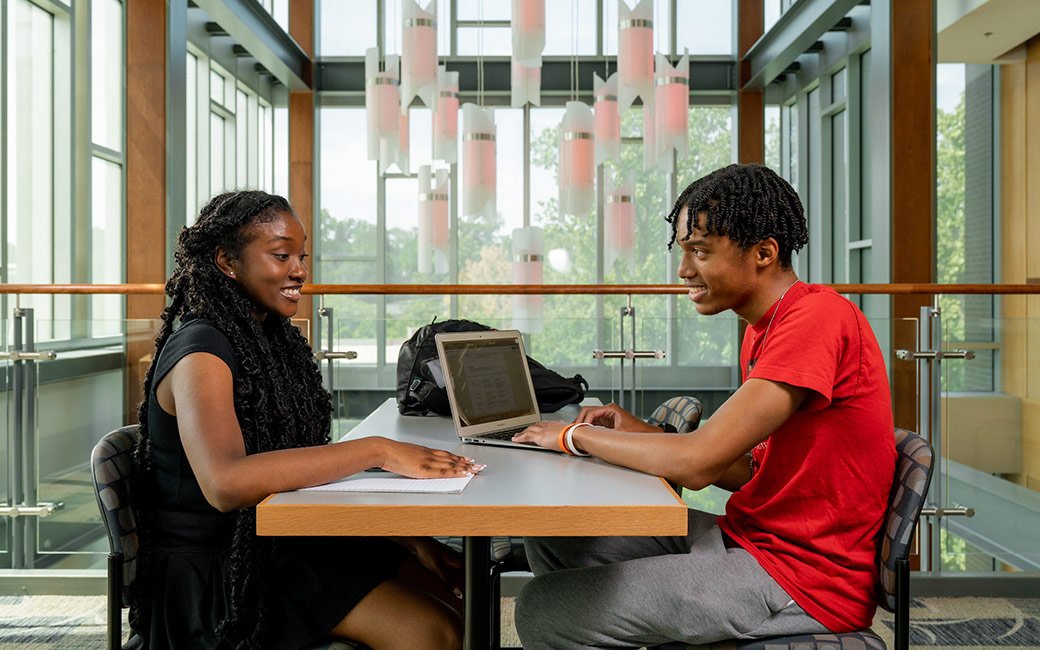 Students sit at desk talking