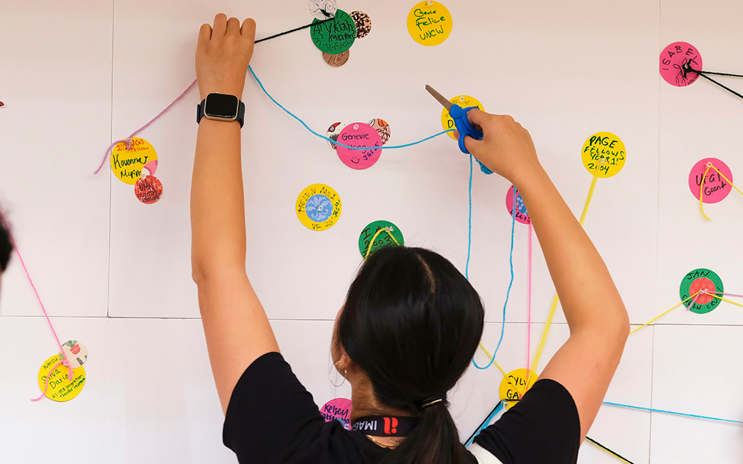 A person adds yarn to a wall.