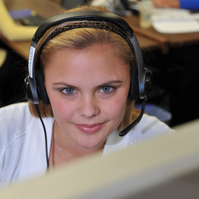 Female student wearing headphones studies computer monitor